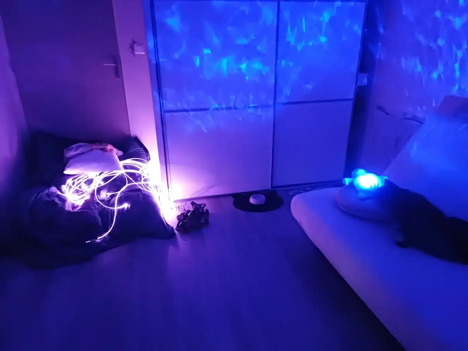 Chambre aménagée en espace d'autorégulation, avec fibres lumineuses, coussins et veilleuse projetant des reflets d'eau