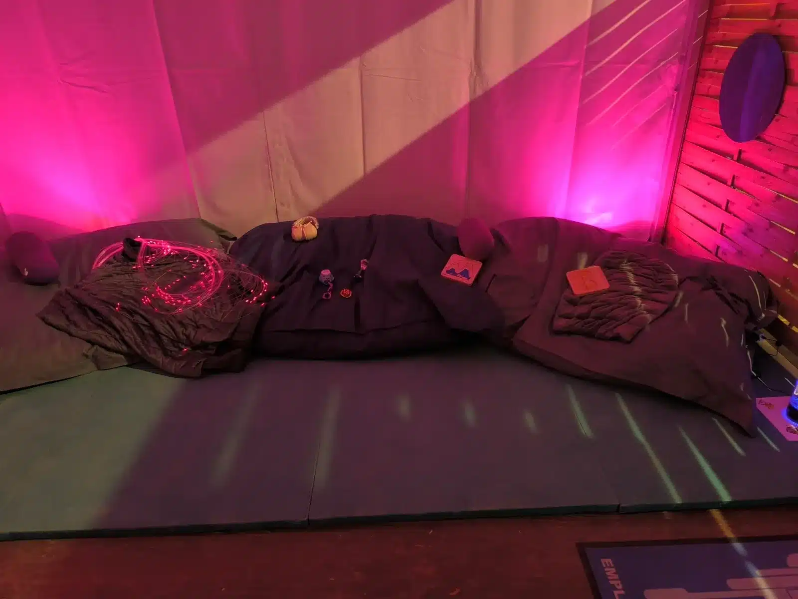 Espace sensoriel de festival aménagé avec poufs, couvertures lestées et fibres lumineuses