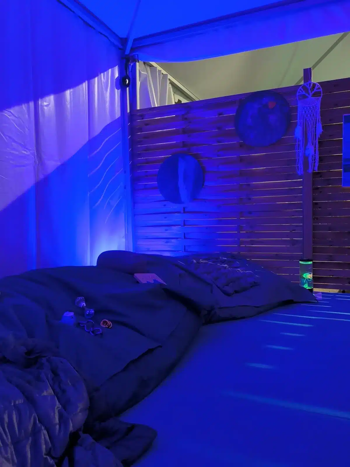 Tente calme d'un festival éclairée en bleu, avec coussins et attrape-rêves