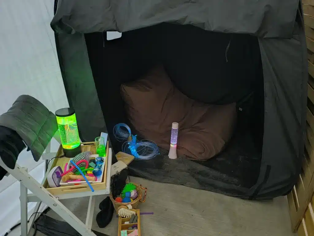 Tente calme sous toile noire avec pouf, fibres optiques, lampes et objets sensoriels