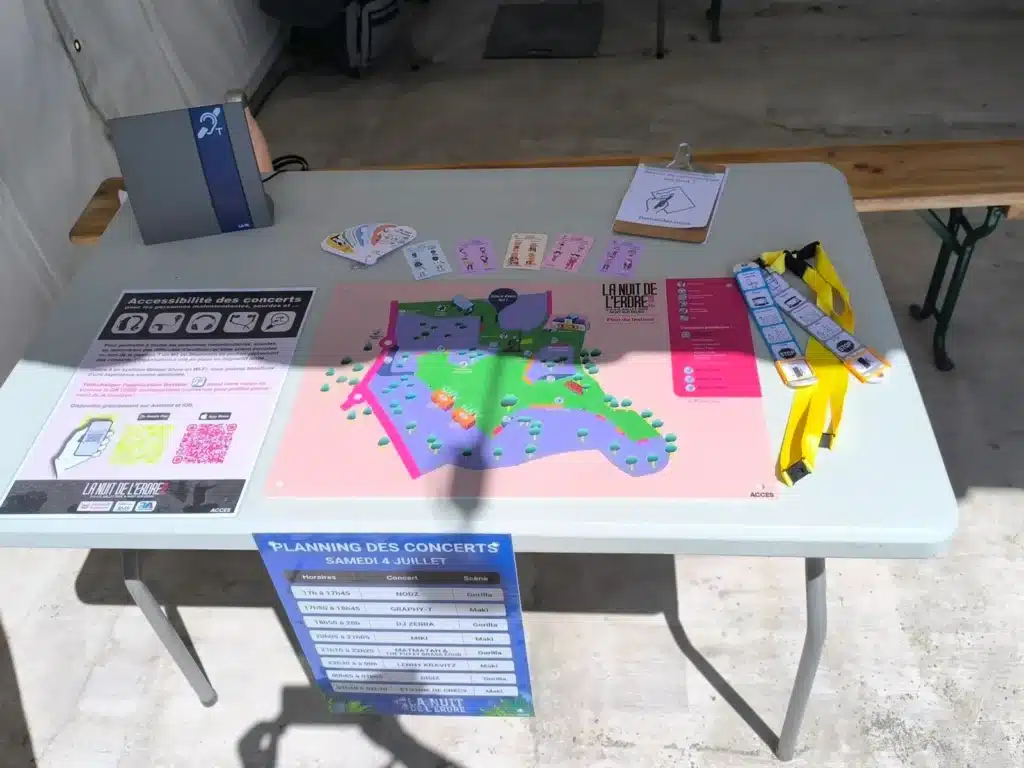 Stand d'accessibilité de festival : plan illustré, cartes de communication et dispositif d'écoute